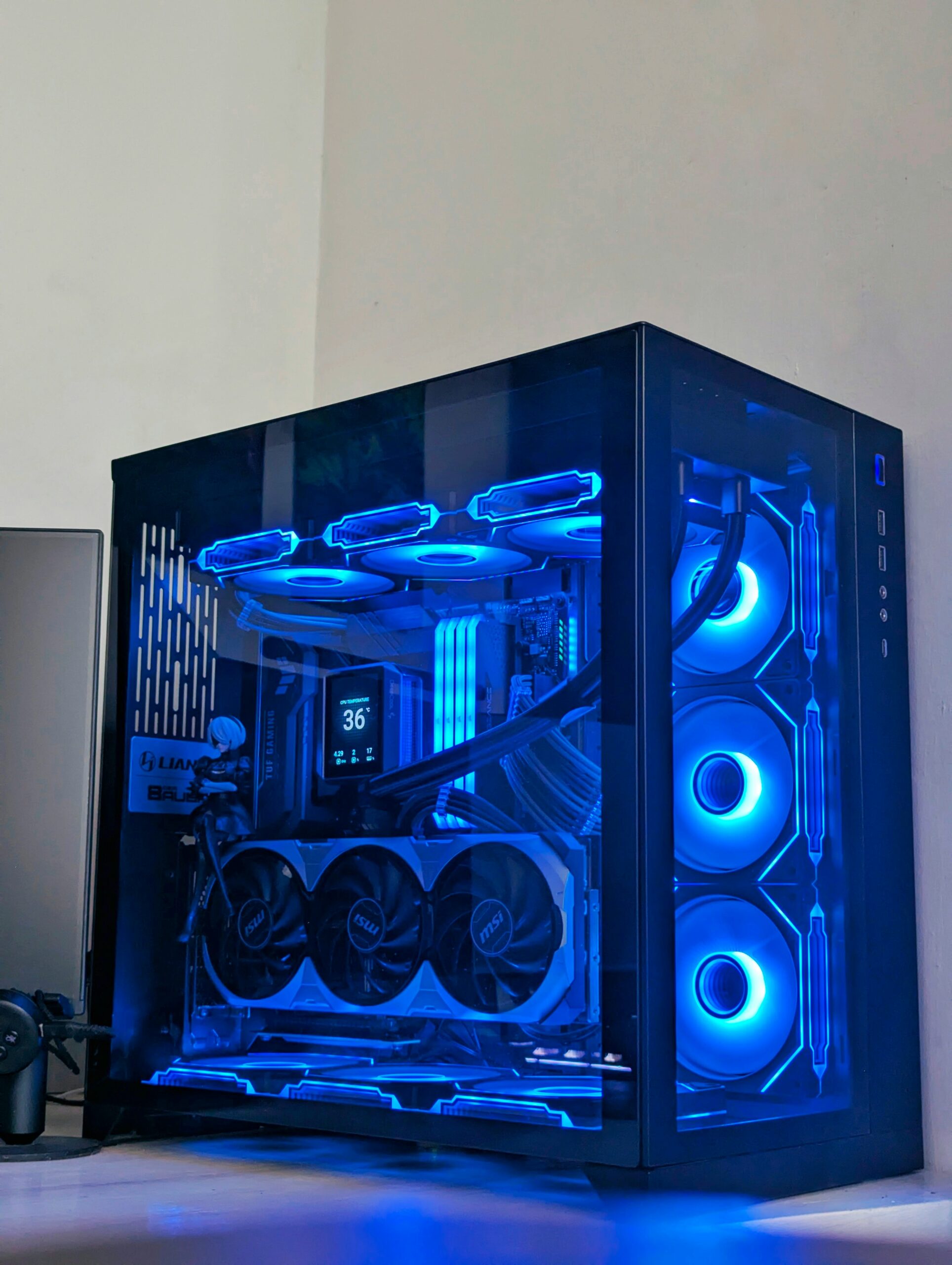 A custom desktop gaming PC with a glass side panel, blue LED lighting, three front fans, and visible internal components on a desk.